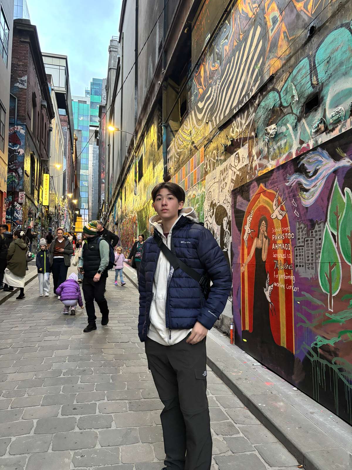 Elijah standing in a narrow lane lined with colorful graffiti murals